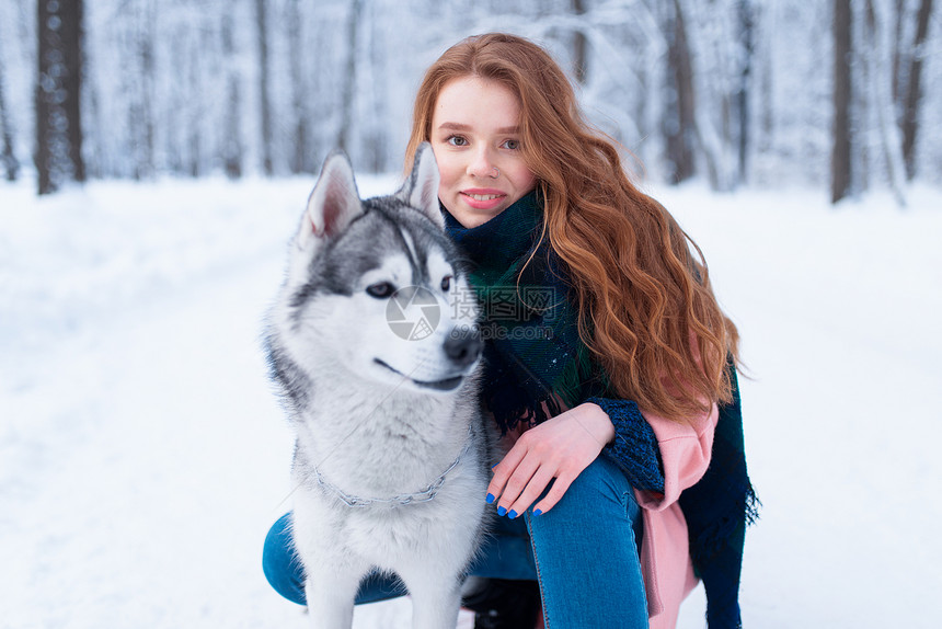 下雪的冬天年轻女子带着狗狗在公园一起在户外图片