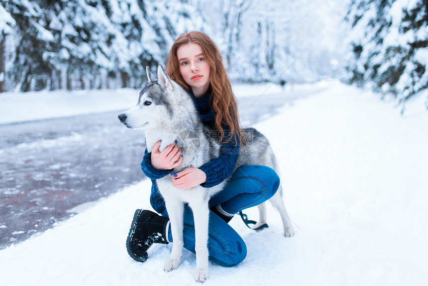 下雪的冬天年轻女子带着狗狗在公园一起在户外图片