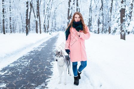冬天美丽的女人带着可爱的狗在外面散步图片