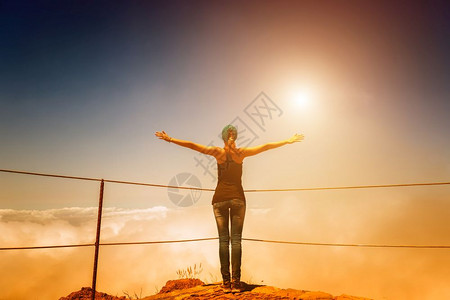 女人站在阴云的山顶上日落时有栅栏脚下印山顶上女人背景图片