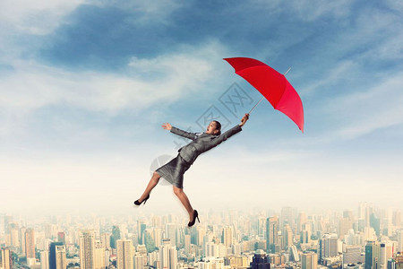 一个惊恐的女人手里拿着红伞在空中飞翔惊恐的女人撑着伞在天空飞翔图片