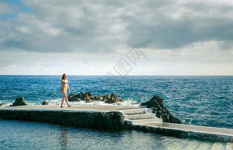 女人在海洋的码头上行走在阴云的一天脚下马德拉女人在海洋的码头上图片