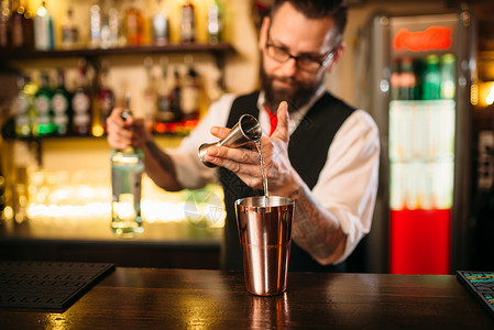 酒制作在餐厅用金属玻璃杯倒酒精饮料的保背景