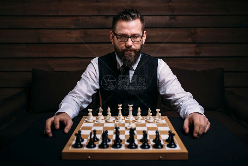 男玩家在眼镜中的男玩家坐在棋板上与类组策略游戏概念男玩家在棋类板上与组图片