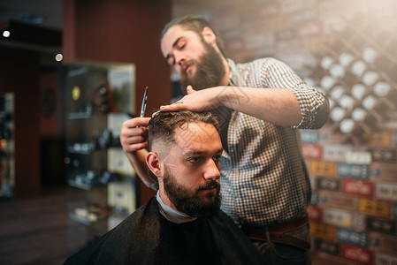 理发师剪发的顾客男人在黑色沙龙披风理发店背景背景图片