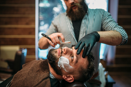 理发师在店用直剃刀刮客户的胡须图片