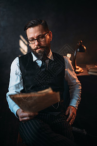 身戴眼镜的留胡子男肖像读手写文字身着背面反光灯的桌子作家记者文学作博客或诗人概念面戴眼镜的留胡子男读手写文字背景图片