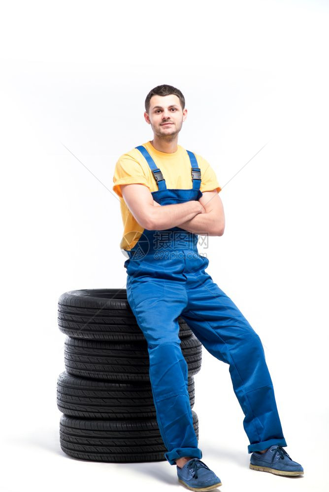 身穿蓝色制服的工人坐在汽车轮胎上图片
