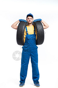 穿蓝制服的车轮工人手持汽胎图片