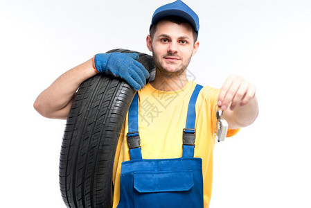 穿蓝制的工人手持轮胎和汽车钥匙图片
