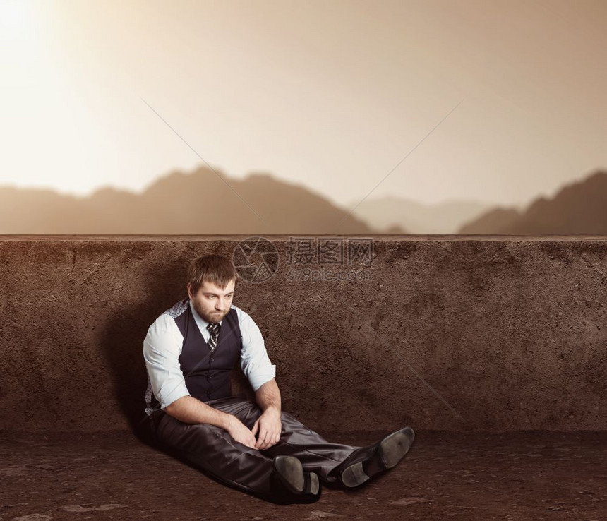 坐在沙漠的地板上压抑男人肖像图片