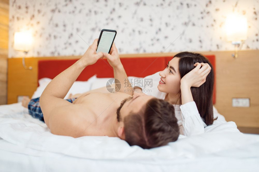 快乐的情侣在床上看手机图片