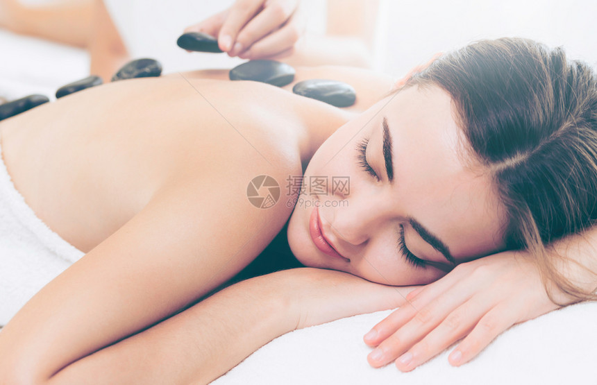 在美容院接受专业师的热石按摩治疗图片