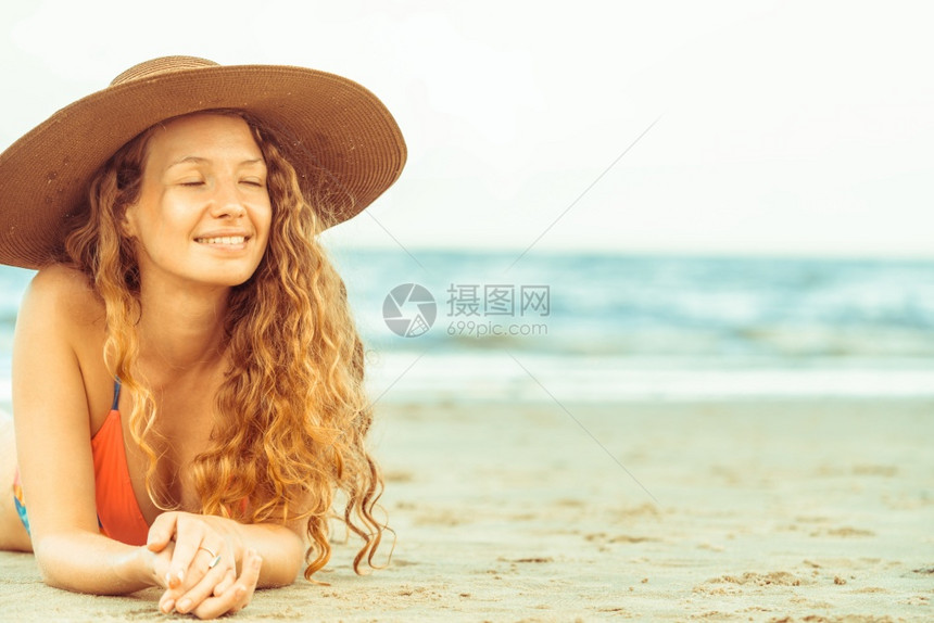 年轻女子穿着比基尼躺在沙滩上图片
