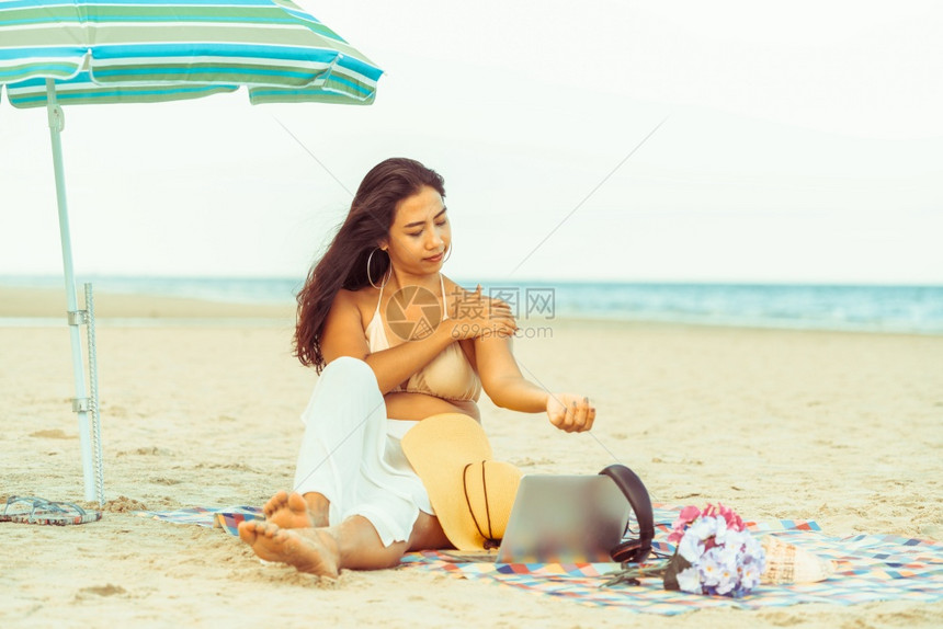 夏天坐在热带沙滩上的年轻女子图片