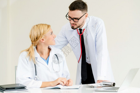 医院办公室的医生与站在她身边的另一名医生交谈时写下病人报告图片
