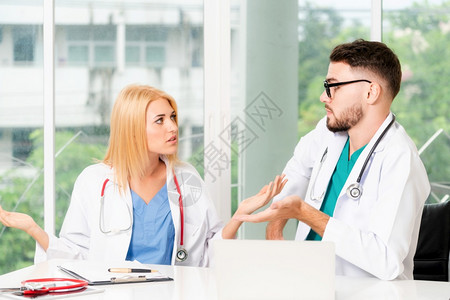 年轻女医生与坐在她身边的男医生交谈医疗服务和保健图片