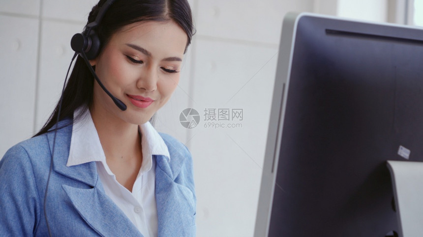 客户支助代理或呼叫中心头盔在台式计算机上工作同时通过电话支持客户图片