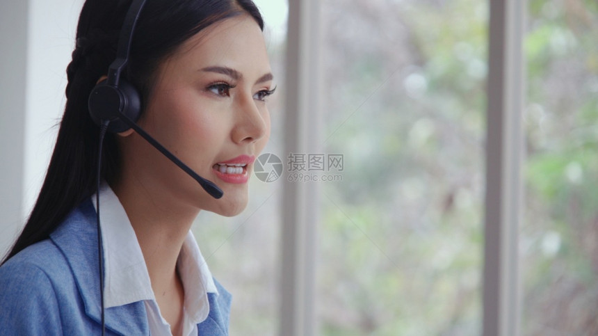 客户支助代理或呼叫中心头盔在台式计算机上工作同时通过电话支持客户图片