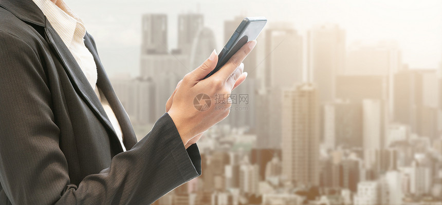 在现代城市背景上用移动电话的商人互联网概念图片