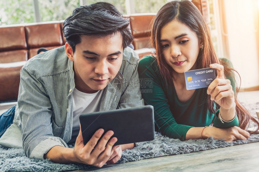 年轻夫妻使用信用卡在家中网购图片
