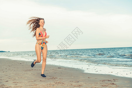 外国美女穿着泳衣在海边沙滩上奔跑背景图片