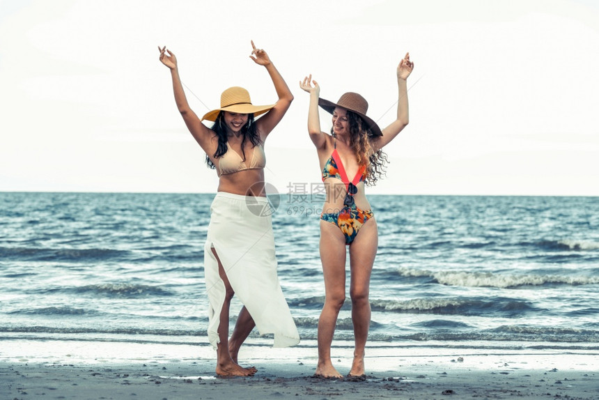 一对青年女闺蜜穿着比基尼在热带沙滩上游玩图片