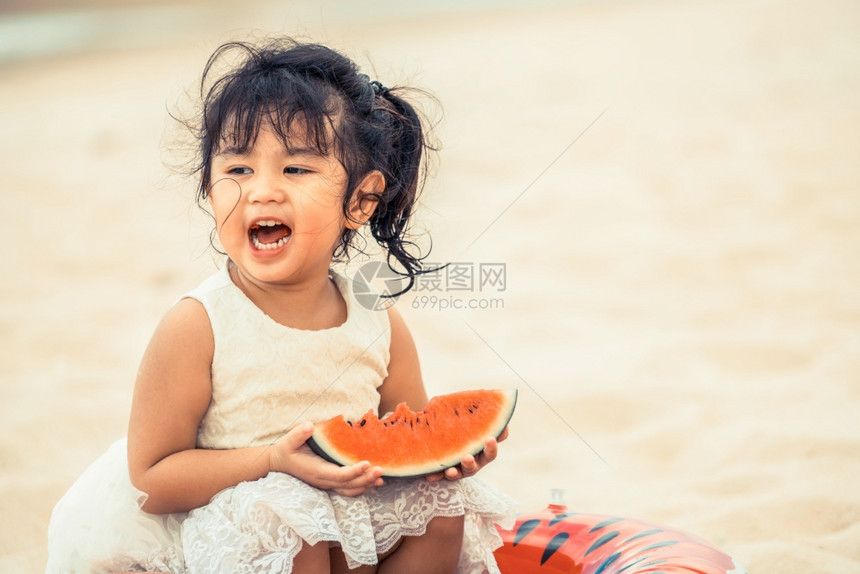 可爱小女孩海滩上吃西瓜图片