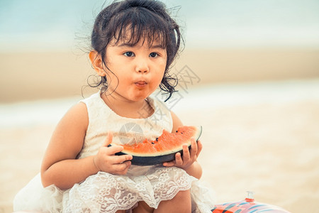 可爱小女孩海滩上吃西瓜图片