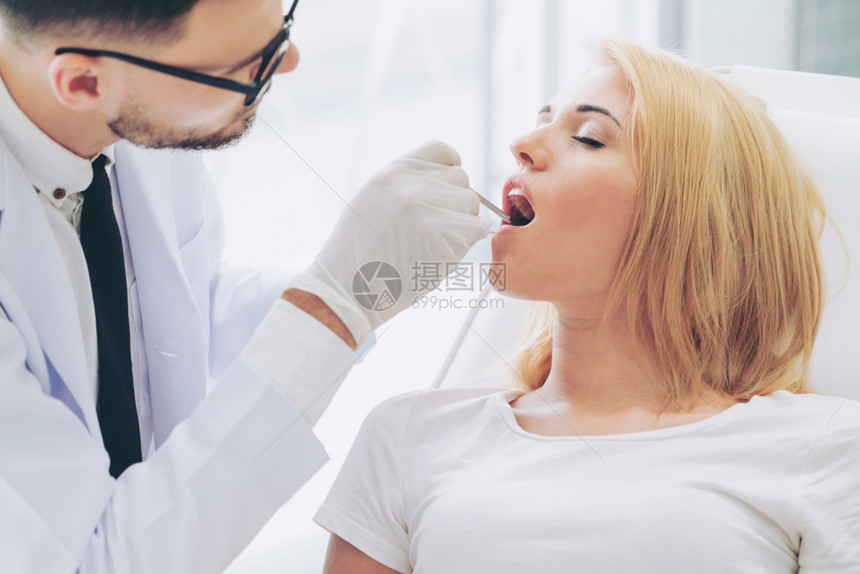 牙医检查在帮女病人检查牙齿图片