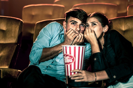 一对情侣在电影院看恐怖片感到害怕图片
