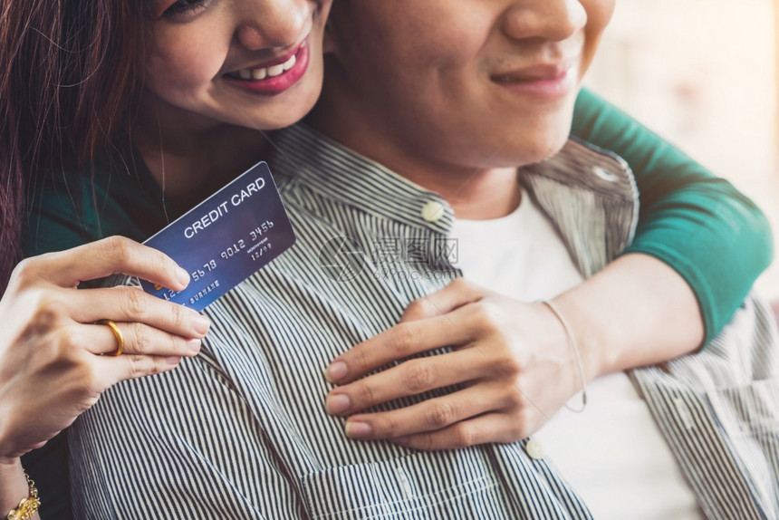 年轻夫妇使用信卡在家中的互联网站上在线购物信用卡号码是假冒的信用卡上没有个人信息网上商业购物概念图片