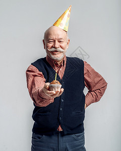 微笑的老人带着帽子展示蛋糕图片