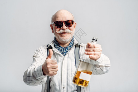 老男人拿着一瓶好酒灰色背景成熟老男人拿着一瓶好酒图片
