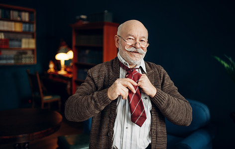 大胡子在起居室长大成人年老商长男子在家庭办公室打领带图片