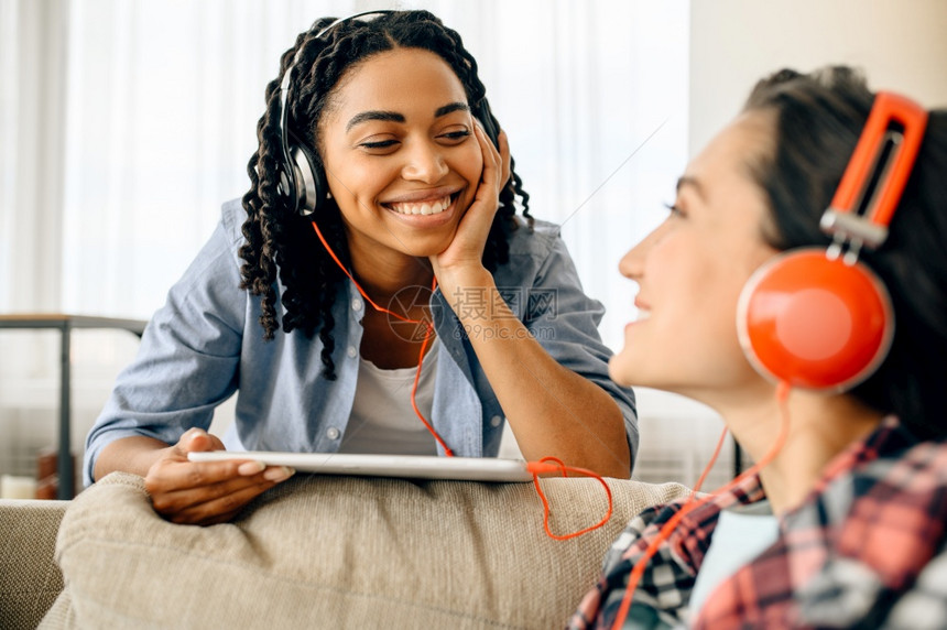 两个快乐的女子在家里听音乐图片
