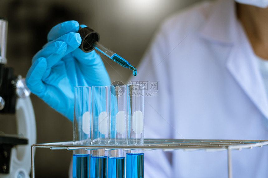 科学家穿戴实验室大衣和防护服从事实验室和发展概念中的测试管研究或调查图片