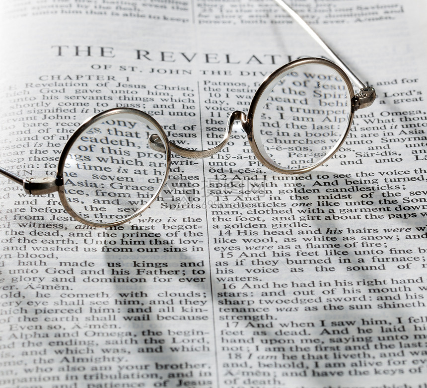 古老的圆眼镜放在圣经的一页上图片