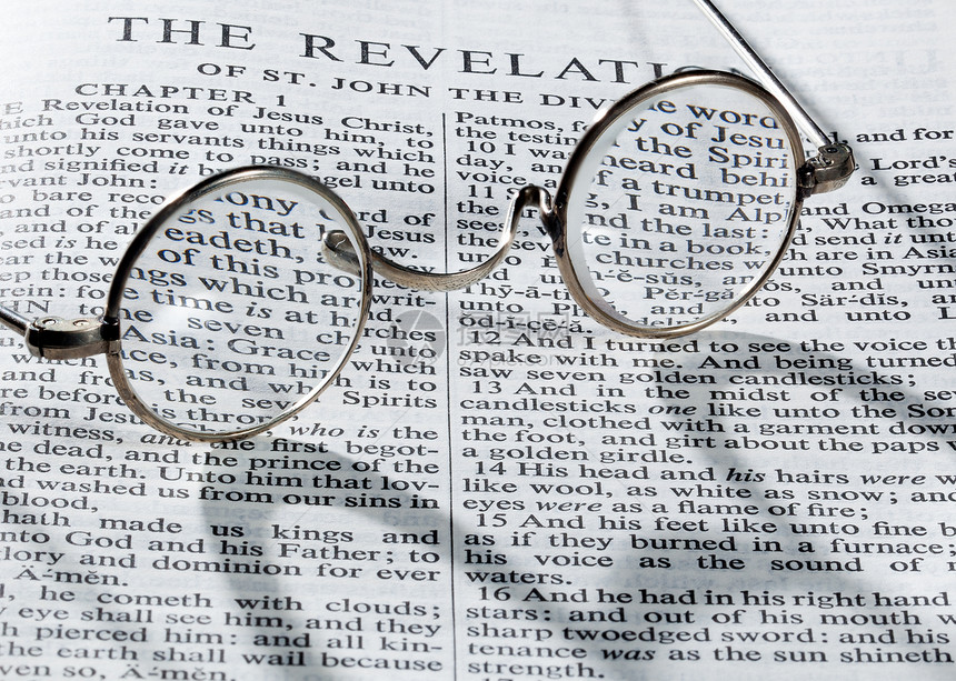古老的圆眼镜放在圣经的一页上图片