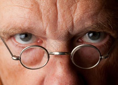 一位年长男画像焦点放在放大镜上眼睛模糊显示视力差图片