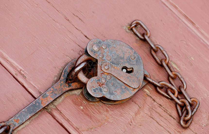 生锈的旧锁和链紧着一扇门图片