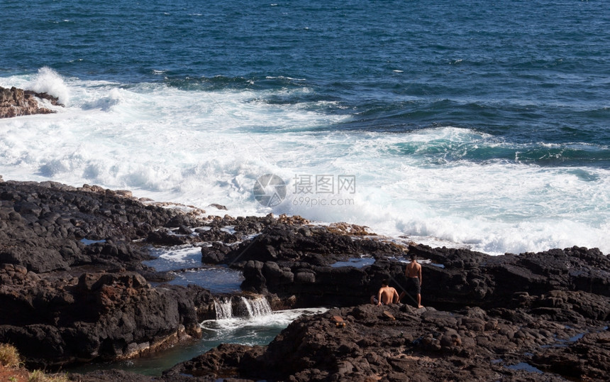 白色的海浪往岸边拍打腐蚀着岩石图片