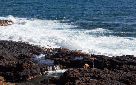 白色的海浪往岸边拍打腐蚀着岩石图片