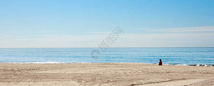 美女独自坐在沙滩上望着碧蓝的海图片
