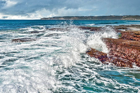 海岸上撞岩石的强烈海浪图片