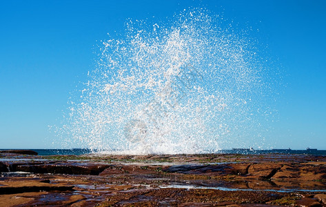 当海浪撞击岸的岩石时图片