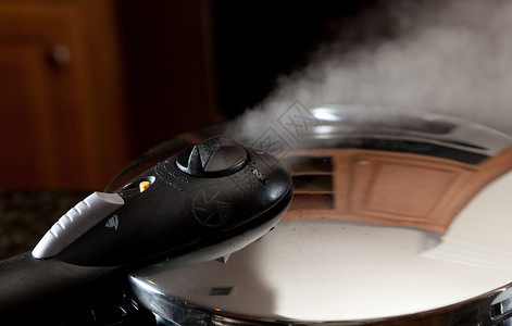 蒸摆脱压力炊具盖与现代厨房的反射图片