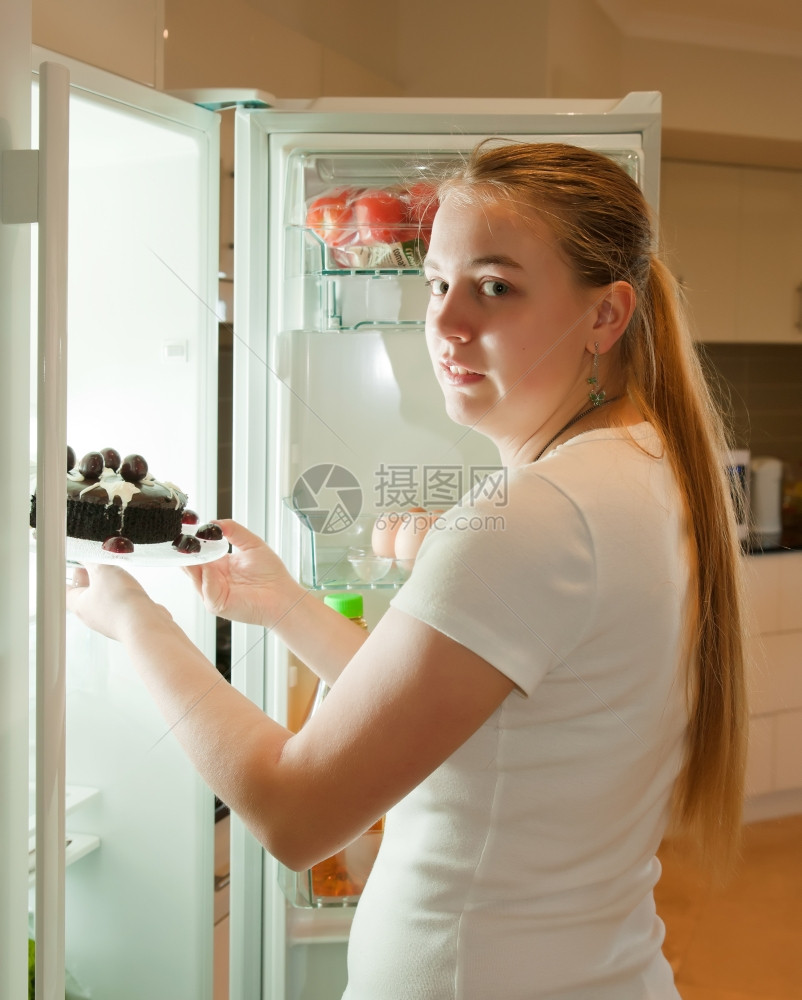 年轻妇女从冰箱里拿食物吃宵夜图片