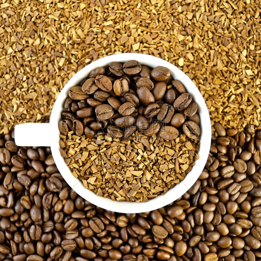谷类和咖啡颗粒背景上的白色杯子中有咖啡豆和谷物图片