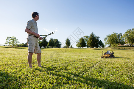 剪草坪具有挑战任务用手工砍草剪割大坪用背景的割草机背景